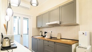 A modern kitchen with grey cabinets, a wooden countertop, a built-in oven, and a water dispenser. - Lilla Eco House Vaticano (Rome)