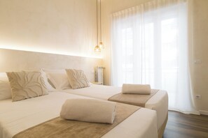 A hotel room with two beds, a large window with sheer curtains, and a hanging light fixture. - Lilla Eco House Vaticano (Rome)
