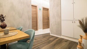 A modern hotel room with a wooden table, teal chairs, a large wardrobe, and a small plant. - Lilla Eco House Vaticano (Rome)