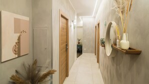 A hallway with wooden doors, a framed artwork on the wall, and a shelf with decorative items. - Lilla Eco House Vaticano (Rome)