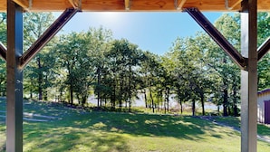 Área externa coberta com vista para um campo gramado e árvores.