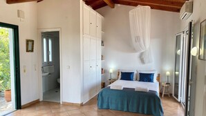 A bedroom with a bed, a wardrobe, a bathroom, and a large window. - Villa Pelagos & guest house, undoubtedly has one of the best views in Corfu. (Corfu)