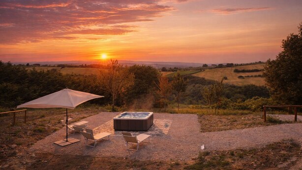 Een hottub met een houten terras, een witte parasol en loungestoelen in een pittoreske buitenomgeving.