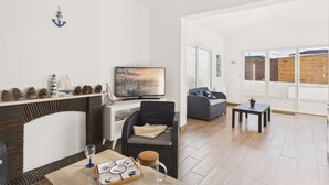 Een moderne woonkamer met een open haard, een flatscreen televisie en een eethoek met een tafel en stoelen.