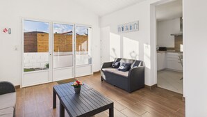Een ruime woonkamer met een bank, een salontafel en uitzicht op een tuin door een schuifdeur.