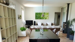 A modern dining area with a glass-top table, clear chairs, a white shelving unit, and a flat-screen TV. - Magnificent villa with private pool in a quiet location (vidauban)