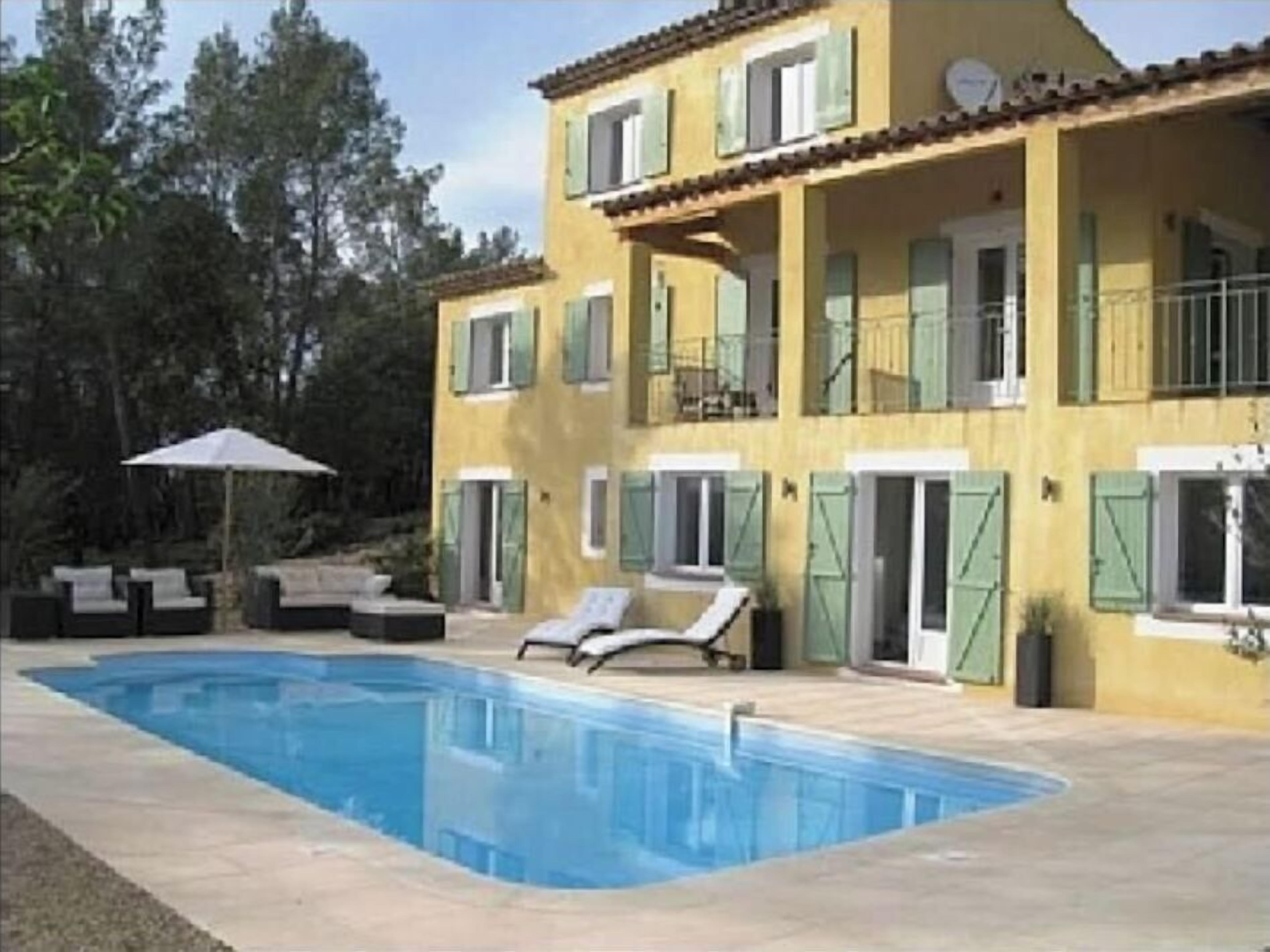 A two-story building with a swimming pool, outdoor seating, and a balcony.