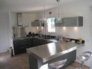 A modern kitchen with stainless steel appliances, a central island, and pendant lighting. - Magnificent villa with private pool in a quiet location (vidauban)