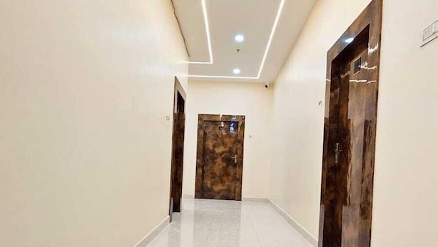Un pasillo con piso pulido, iluminación empotrada y una puerta al final.