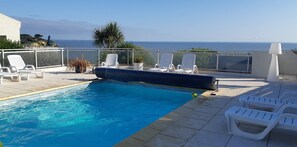 Una piscina con sillas de descanso y vistas al mar.