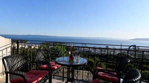 Ein Balkon mit Tisch und Stühlen mit Blick auf eine Stadtlandschaft und das Meer.