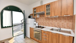 Eine Küche mit Holzschränken, einem Herd, einer Spüle und einem Kühlschrank.