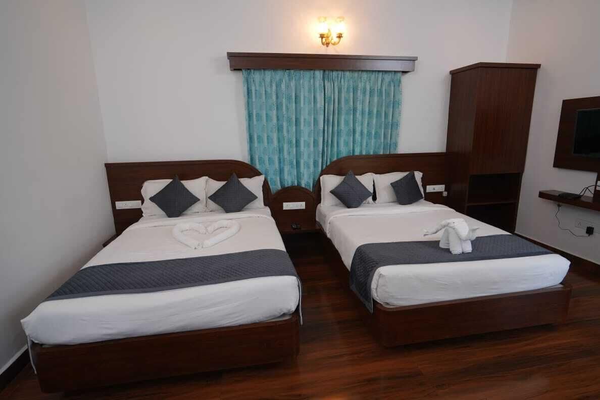 Habitación de hotel con dos camas, cabecero de madera, cortina color turquesa, armario de madera y un televisor en la pared.
