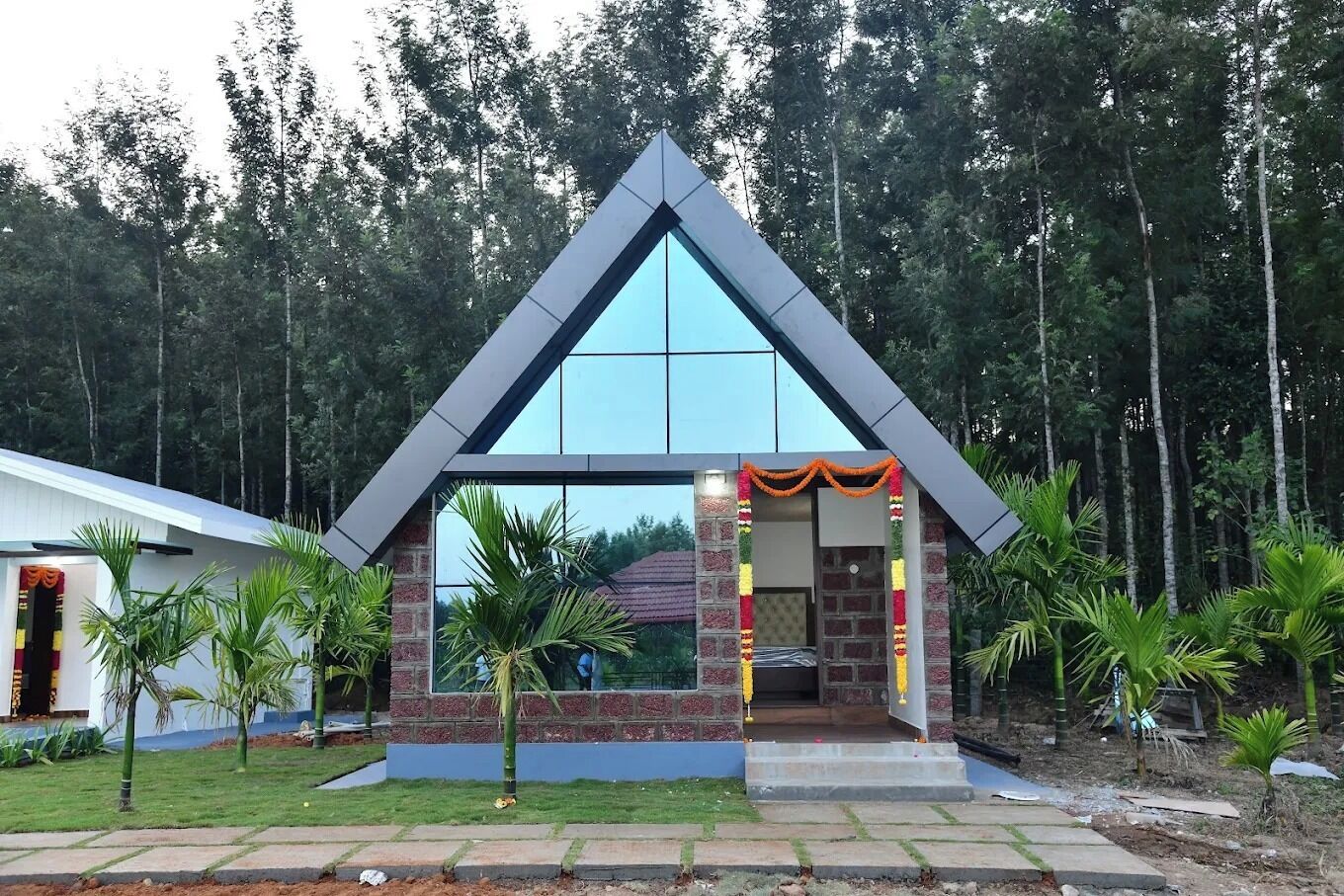 A modern building with a triangular roof and large windows, surrounded by greenery.