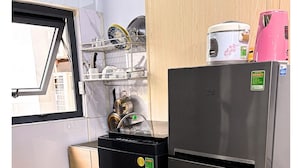 Une cuisine compacte équipée d’un réfrigérateur en acier inoxydable, d’un lave-vaisselle noir et d’une fenêtre donnant sur l’extérieur.