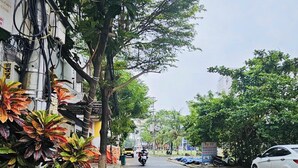 Une rue avec un trottoir, des voitures garées et une moto.