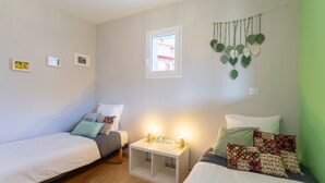Een kamer met twee bedden, een klein nachtkastje met verlichting, een raam en decoratieve wandpanelen.