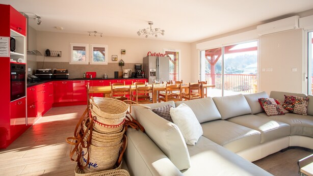 A modern kitchen with red cabinets, a dining area with wooden chairs, and a large window offering a view. - Bed and Breakfast 'Chambre - Orchis' with Mountain View, Wi-Fi and Air Conditioning (Aroue-Ithorots-Olhaïby)