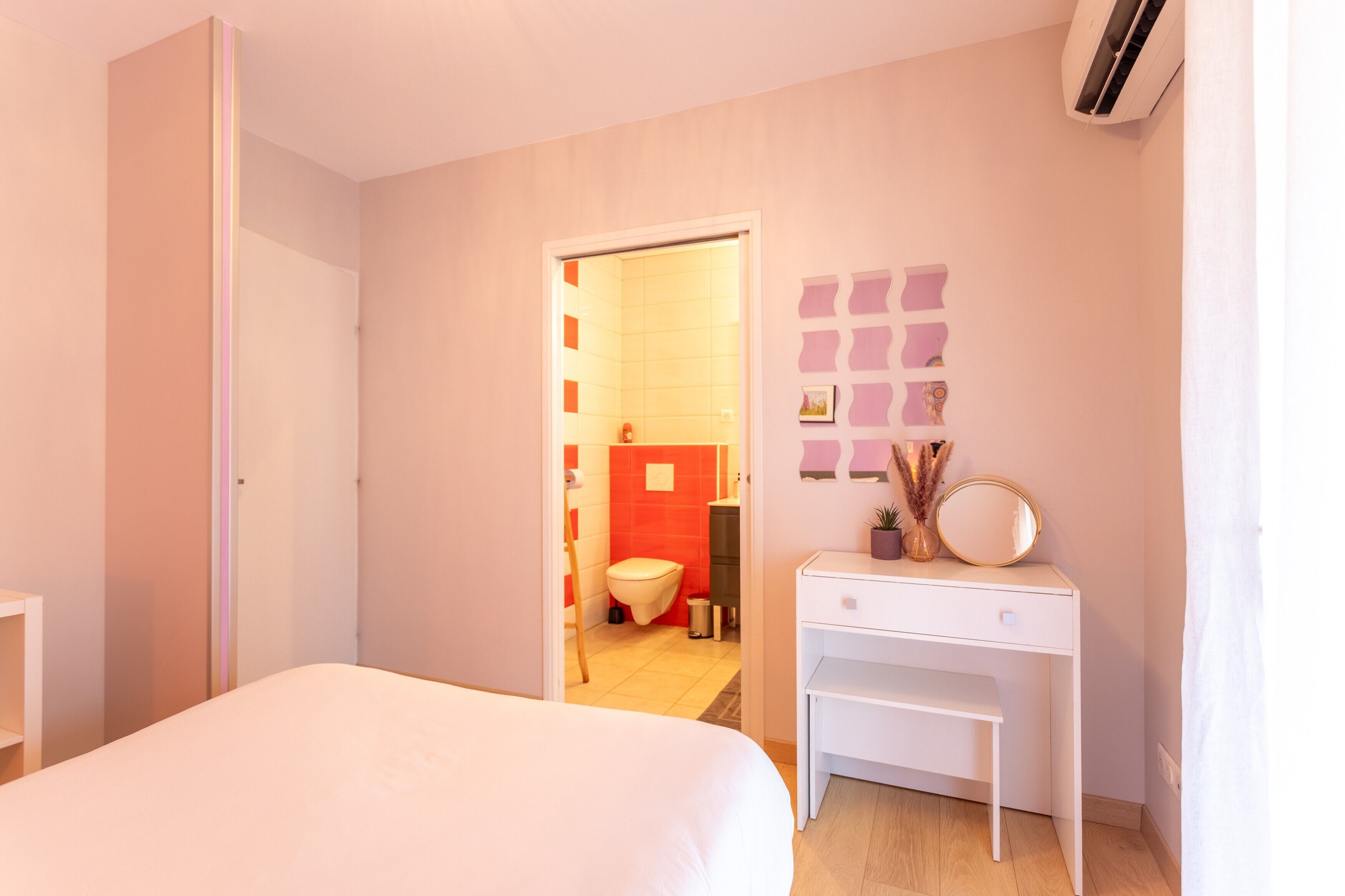 A bedroom with a bed, a desk, and a bathroom visible through an open door.