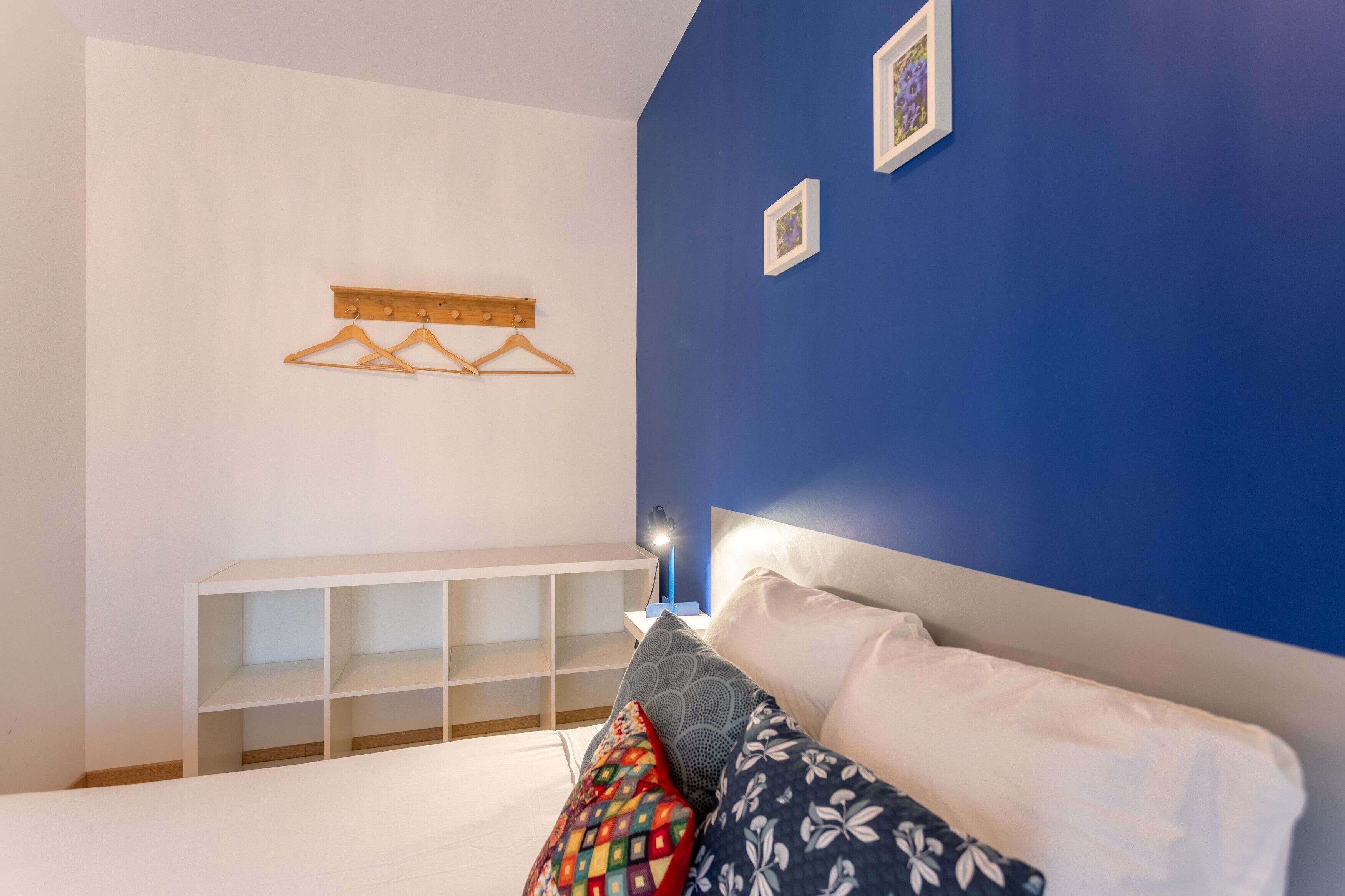 Een slaapkamer met een bed, een witte console tafel, een blauwe wand en een wandlamp.