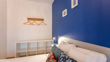 Een slaapkamer met een bed, een witte console tafel, een blauwe wand en een wandlamp.