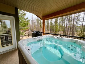 A hot tub on a covered patio with a view of a forest.
