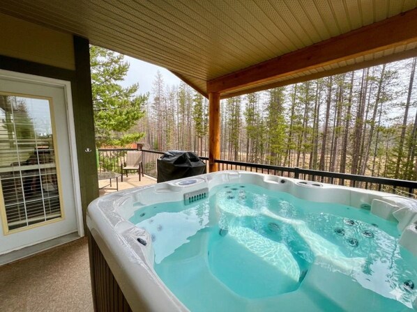 A hot tub on a covered patio with a view of a forest.