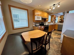 A compact kitchen with wooden cabinets, a built-in microwave, a stove, and a sink. - Set at the base of Kimberley Alpine Resort, this spacious 5-bedroom, 4-bath townhouse comfortably suits two average-sized families. Ski in and out near the unit, walk about 2 minutes to the Express Quad Chair and base-area dining, then unwind in one (Kimberley)