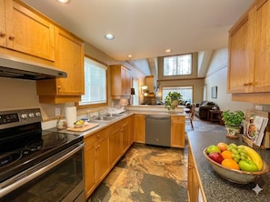 A kitchen with wooden cabinets, a dishwasher, and a stone tile floor.
