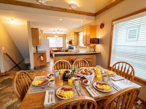 A breakfast setting with a dining table, chairs, and a kitchen area in the background.
