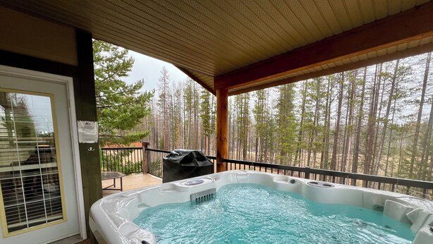 A hot tub with a view of a forest. - Prime Base Location! 5BR, 4BA condo just a 2-min walk to the Express Quad. Ski back to your door. Features 2 hot tubs and a double garage for gear. Enjoy easy access to base restaurants and bars! (Kimberley)