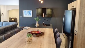 A modern kitchen with a central island, black bar stools, a built-in TV, and pendant lighting. - Contemporary house at the gateway to the Luberon in a peaceful and relaxing setting (Pernes-les-Fontaines)