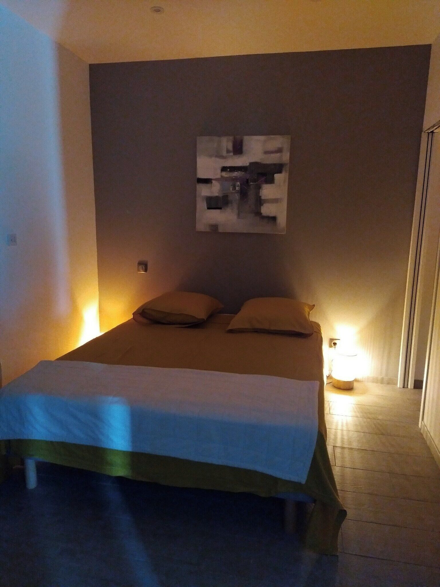 Ett sovrum med en säng, två sänglampor och ett abstrakt konstverk som hänger på väggen.