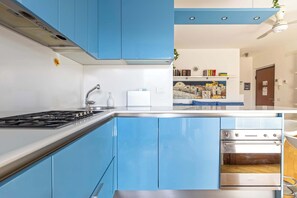 A modern kitchen with blue cabinets, a stainless steel stove, and an oven. - Appartamento Torretta 4 -Immobili e Soluzioni Rent (Bergamo)