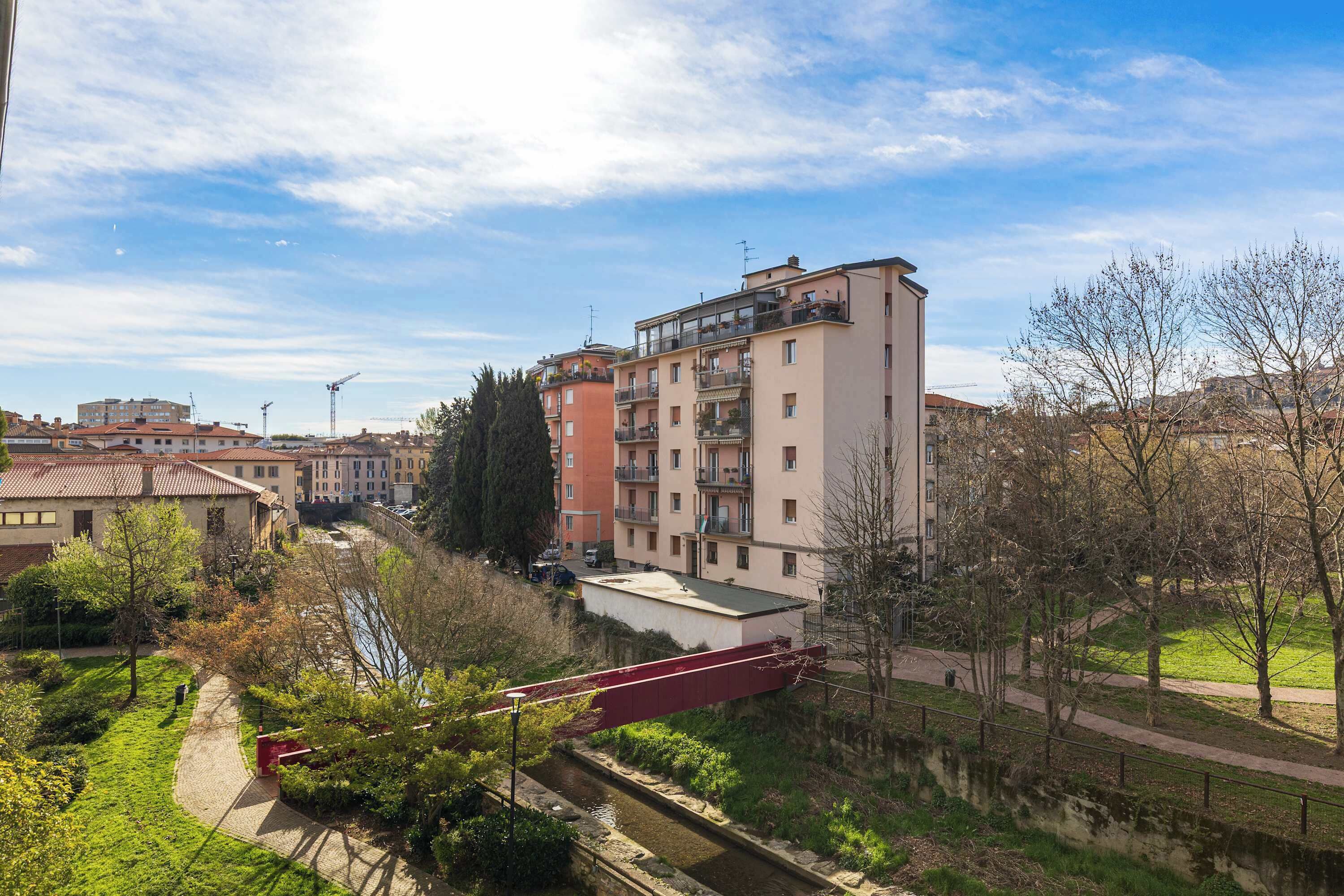 A multi-story residential building with balconies, a river, and a bridge.