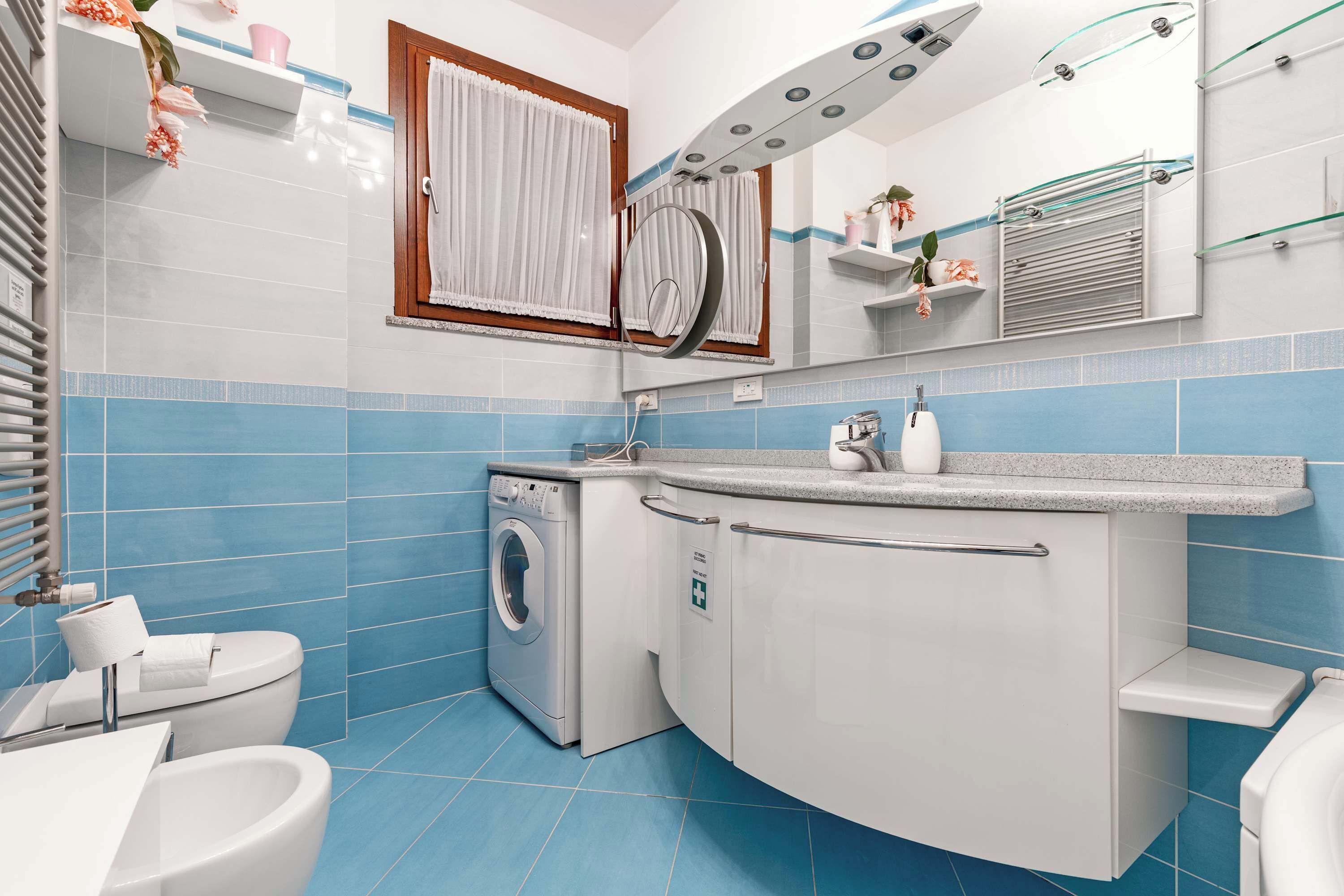 Un bagno moderno con lavatrice, WC e lavandino.