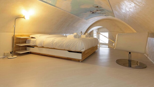 Ein modernes Schlafzimmer mit Bett, Nachttischlampe und Sessel.