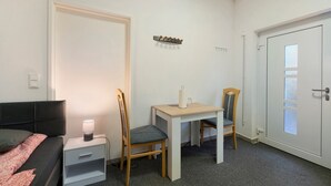 Een slaapkamer met een bed, nachtkastje met lamp, bureau met stoel en een kledingkast.