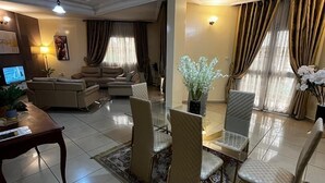 Un ampio soggiorno con zona pranzo, caratterizzato da un lampadario, un televisore e una grande finestra con tende.