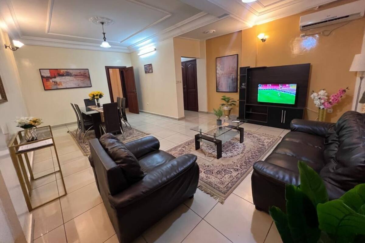 A living room with a sofa, coffee table, TV, and a dining area with chairs and a table.
