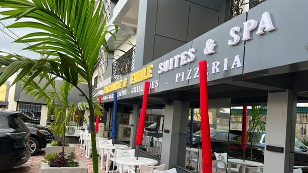 Un edificio con un cartello che indica 'Emile Suites & SPA' e un'area esterna con tavoli e sedie.