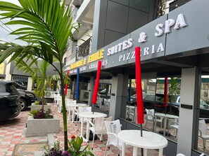 A building with a sign for 'Emile Suites & SPA' and outdoor seating with tables and chairs. - Appart'hôtel Micheline et Emile, Suites & SPA, Bastos (Yaoundé)
