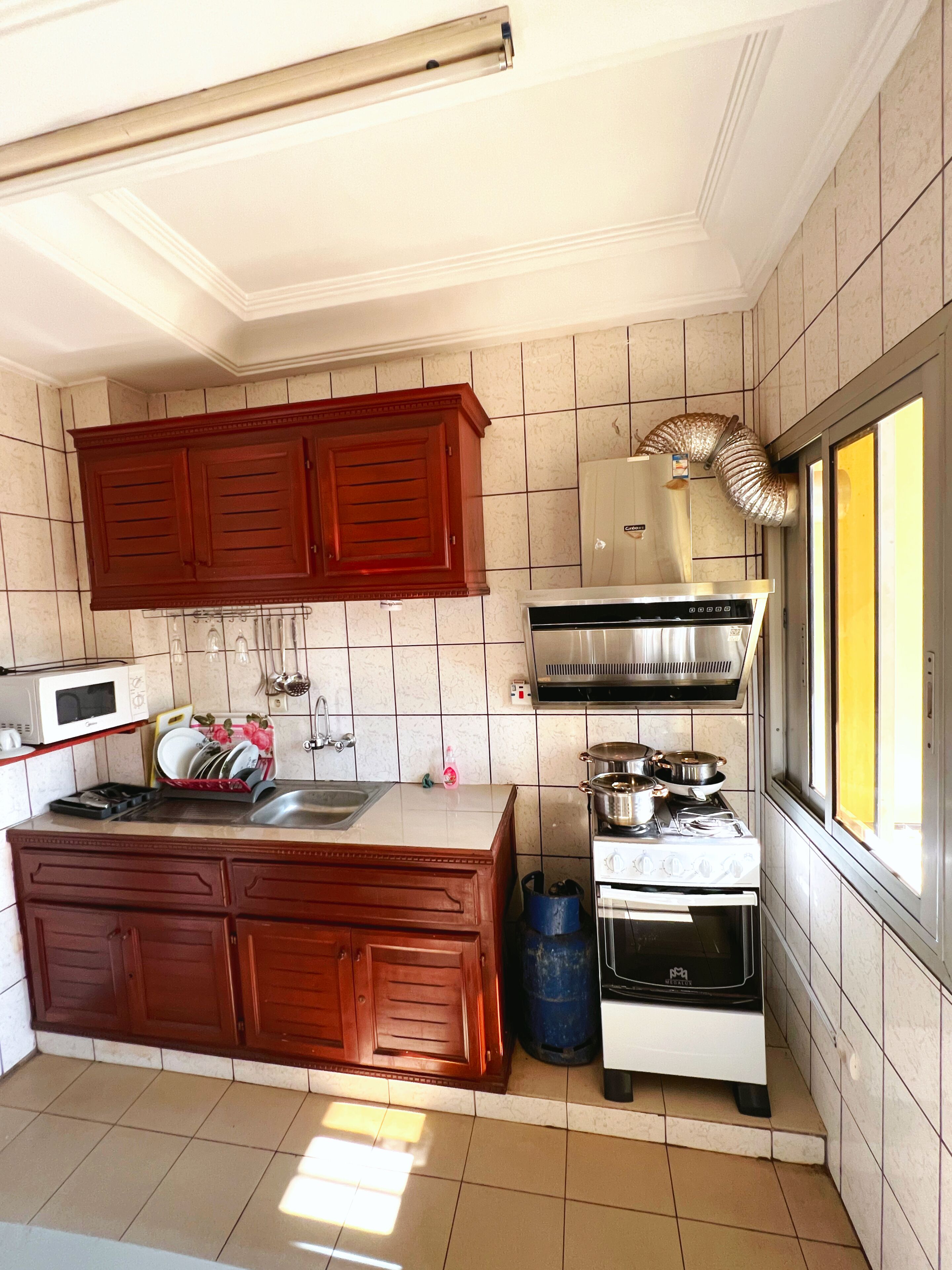 A compact kitchen with a microwave, stove, and wooden cabinets.