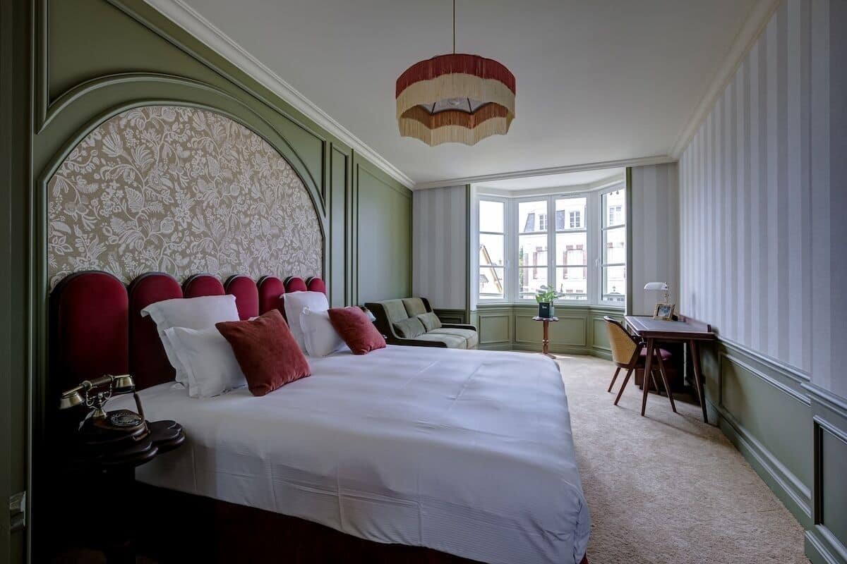 A hotel room with a large bed, a desk, and a window.