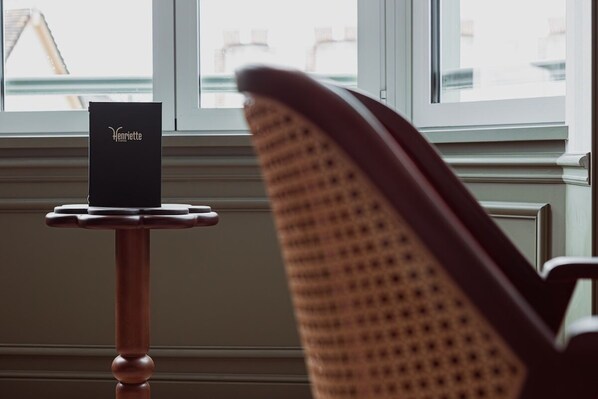 A chair facing a window with a sign on a small table. - VILLA HENRIETTE (Cabourg)