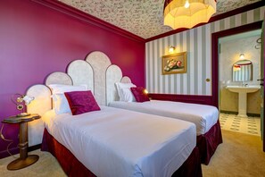 A hotel room with two beds, a vanity with a mirror, and a floral wallpaper design. - VILLA HENRIETTE (Cabourg)