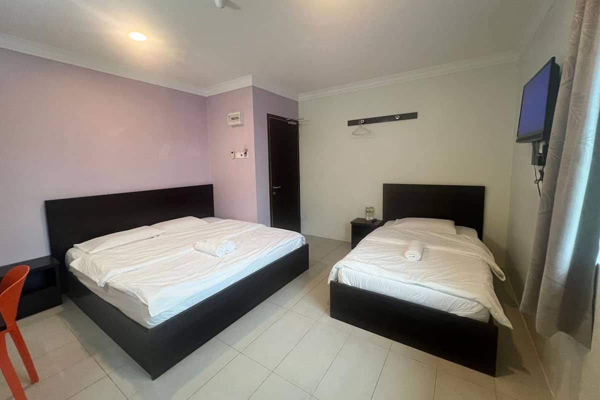 A hotel room with two beds, a TV, and a small table.