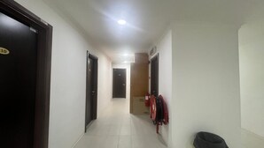 A hallway with doors, a fire extinguisher, and a trash bin.