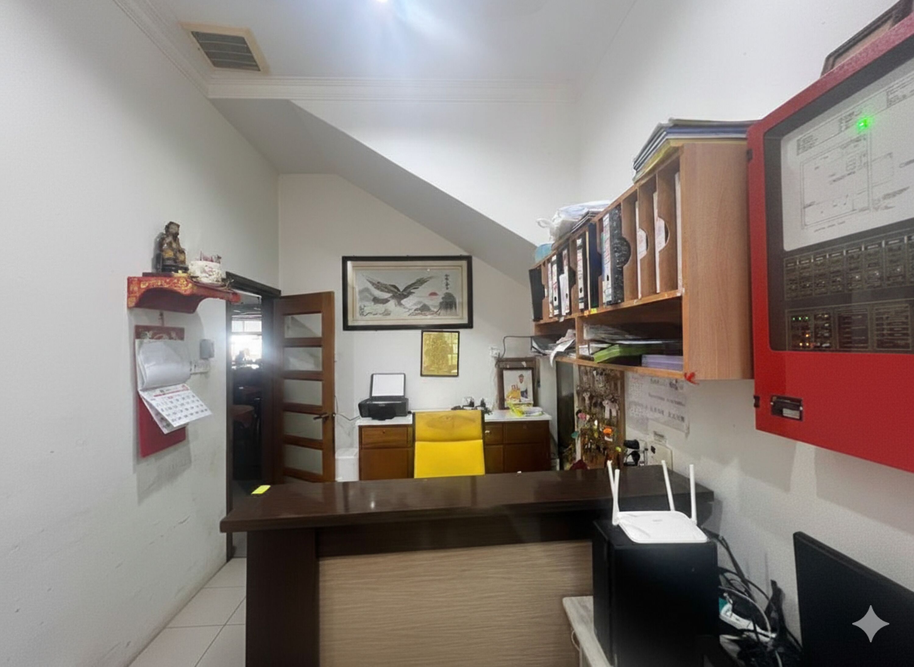 A narrow hallway with a desk, shelves, and a computer.