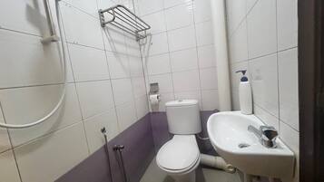 A small bathroom with a toilet, sink, and shower.